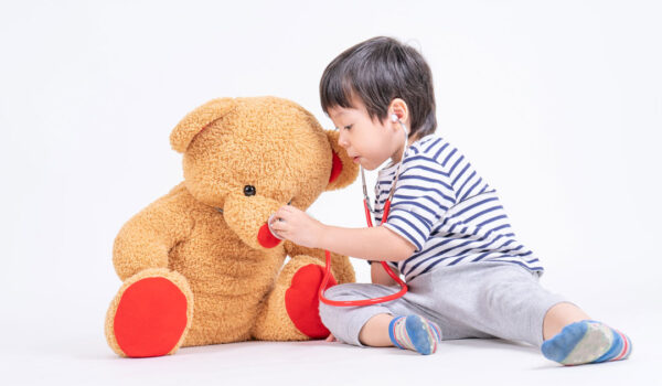 Criança brincando de médico com um urso de pelúcia